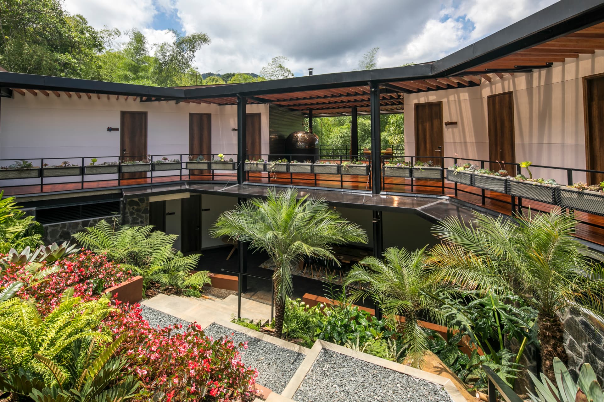 Patio central de Araucana Lodge, una arquitectura abierta entre palmas, helechos y jardines